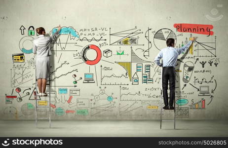 Business strategy seminar. Back view of businessman and businesswoman standing on ladder and drawing sketches on wall