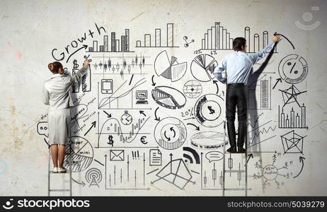 Business strategy seminar. Back view of businessman and businesswoman standing on ladder and drawing sketches on wall