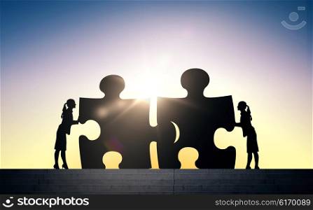 business, strategy, startup, development and people concept - silhouette of two business women connecting puzzle pieces over sun light background