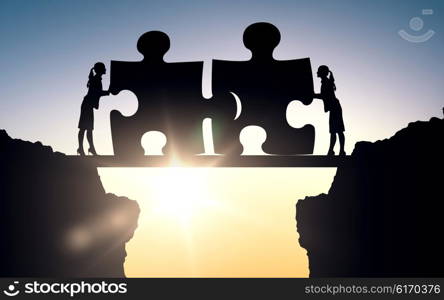 business, strategy, startup, development and people concept - silhouette of two business women connecting puzzle pieces over sun light background