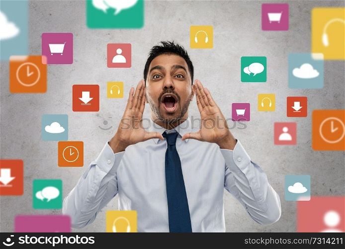 business, stress and people concept - indian businessman shouting or calling over app icons on grey background. indian businessman shouting over app icons