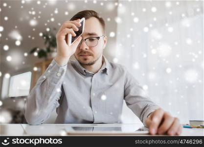 business, stress, fail, technology and people concept - businessman or creative male worker with smartphone at home office over snow