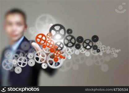 Business structure. Image of businessman touching gear elements. Mechanism concept