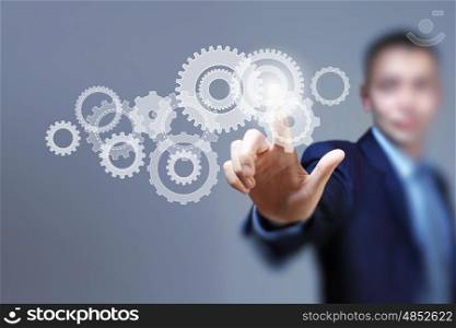 Business structure. Image of businessman touching gear elements. Mechanism concept