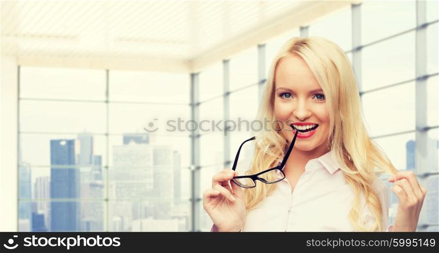 business, style and people concept - smiling businesswoman, student or secretary with eyeglasses over office window with city view background