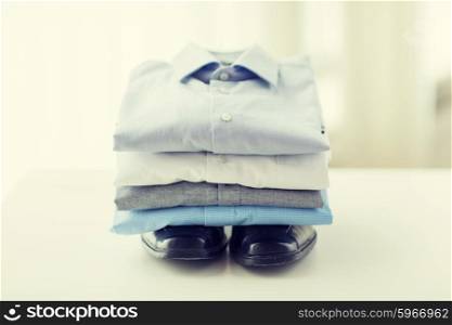 business, style, clothes, housekeeping and objects concept - close up of ironed and folded shirts and formal shoes on table at home