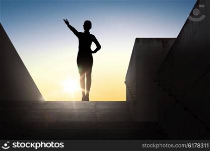 business, success, achievement and people concept - silhouette of woman pointing hand and showing direction standing on stairs over sun light background