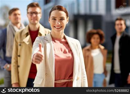 business, success and gesture concept - happy smiling woman with international group of people showing thumbs up outdoor. happy smiling woman showing thumbs up outdoors