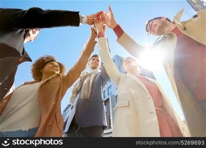 business, success and gesture concept - international group of people or students making high five on city street. group of happy people making high five in city