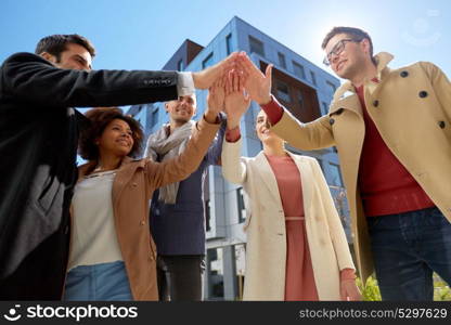 business, success and gesture concept - international group of people or students making high five on city street. group of happy people making high five in city