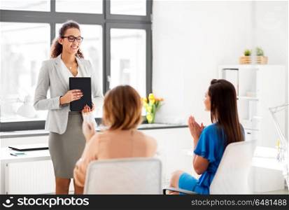 business, success and people concept - businesswomen applauding to colleague with tablet pc computer at office. business team applauding to woman at office. business team applauding to woman at office