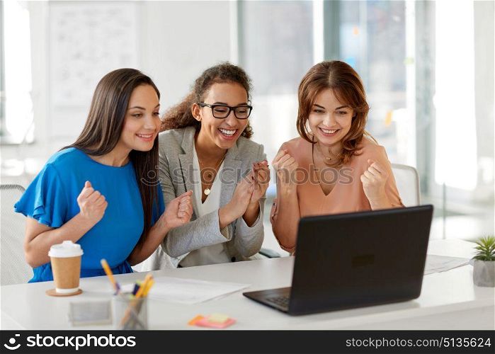business, success and people concept - happy female team or businesswomen with laptop computer celebrating victory at office. happy businesswomen with laptop at office. happy businesswomen with laptop at office