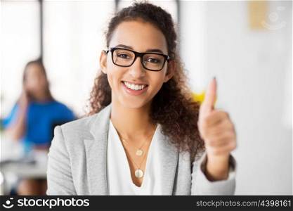 business, success and people concept - happy smiling african american woman in glasses showing thumbs up at office. smiling african woman showing thumbs up at office. smiling african woman showing thumbs up at office