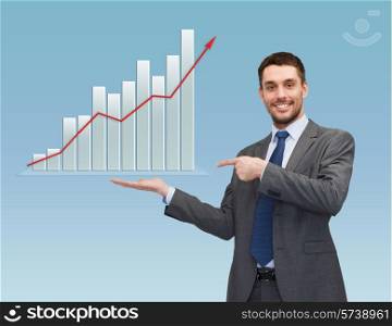 business, success, economics, and people concept - smiling young businessman pointing finger and showing growth chart on palm of his hand over blue background