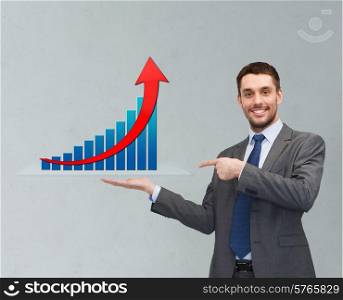 business, success, economics, and people concept - smiling young businessman pointing finger and showing growth chart on palm of his hand over gray background