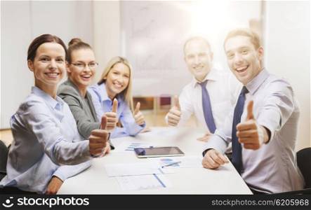 business, success, technology and office concept - smiling business team with tablet pc computer and papers showing thumbs up in office