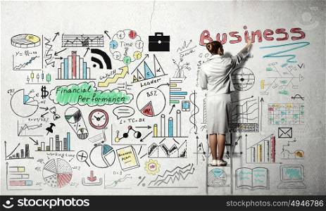 Business successful strategy. Back view of businesswoman standing on ladder and drawing her great plan on wall