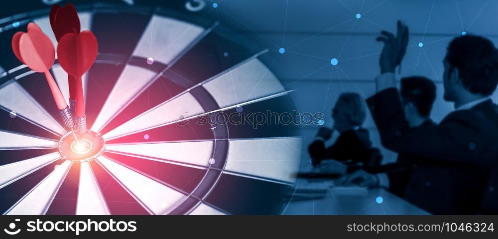 Business Target Goal For Success Strategy Concept - Red dart arrow hitting center goal on the dart board with business people working in background showing precision and success of business target.