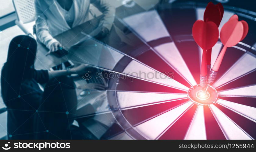 Business Target Goal For Success Strategy Concept - Red dart arrow hitting center goal on the dart board with business people working in background showing precision and success of business target.