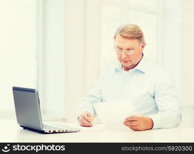 business, tax, office, school and education concept - old man in eyeglasses filling a form at home