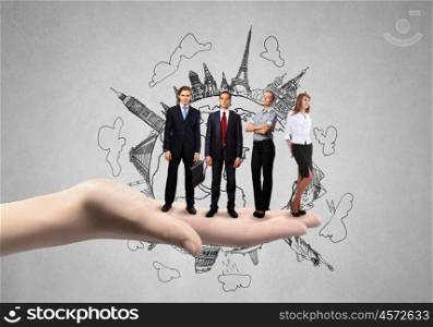 Business team. Business people standing on palm with construction sketch at background