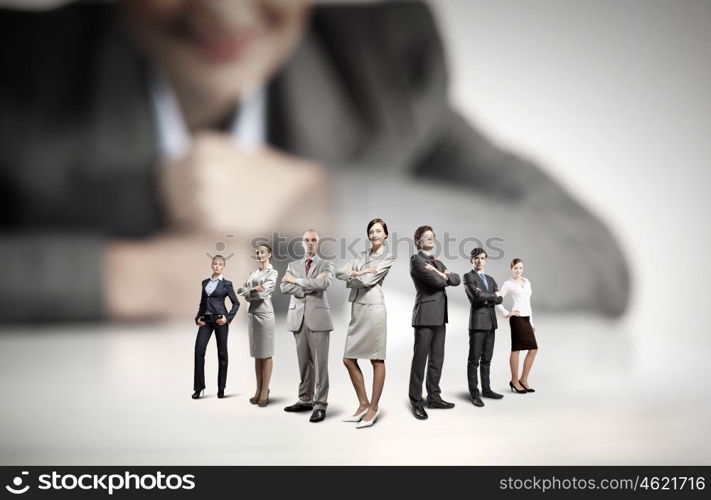 Business team concept. Businesswoman looking at group of businesspeople in miniature