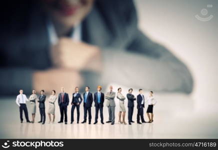 Business team concept. Businesswoman looking at group of businesspeople in miniature