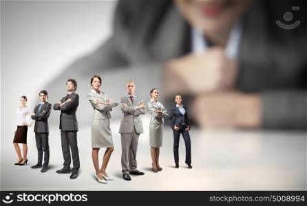 Business team concept. Businesswoman looking at group of businesspeople in miniature