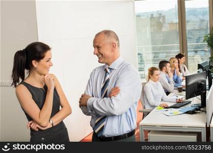Business team conversing with colleagues working in background at office