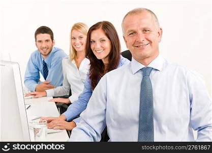 Business team handsome mature manager sitting behind computer table office