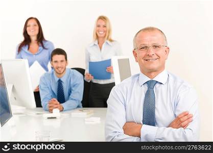 Business team happy mature businessman with attractive colleagues behind computer