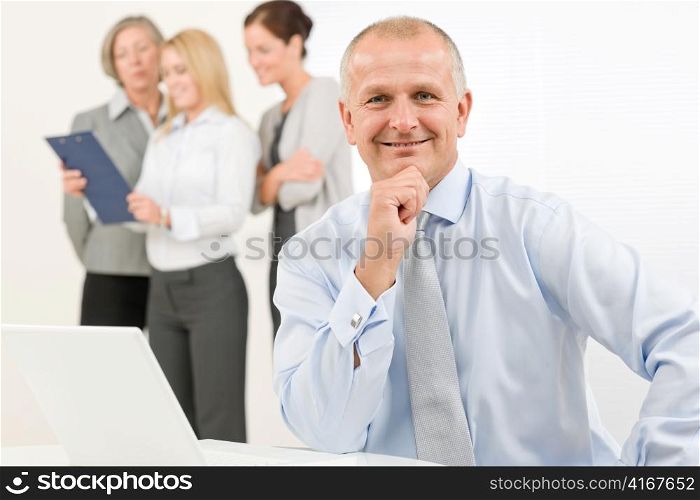 Business team happy mature businessman with attractive colleagues looking file