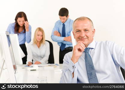 Business team happy mature businessman with attractive colleagues looking files