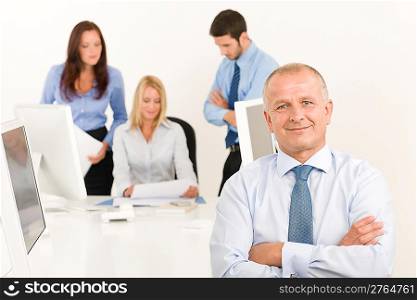 Business team happy mature businessman with attractive colleagues looking files
