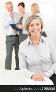Business team happy senior businesswoman with attractive colleagues looking file