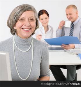 Business team happy senior businesswoman with attractive colleagues looking file