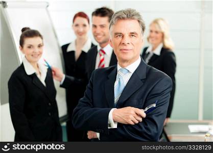 Business - team in an office; the senior executive is standing in front