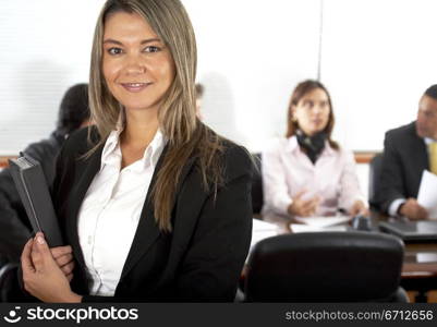 Business team in an office with a businesswoman leading and holding a folder