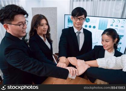 Business team of suit-clad businessmen and women join hands stack together and form circle. Colleagues collaborate and working together to promote harmony and teamwork unity in office workplace.. Businessmen and women join hand stack together, form circle for harmony concept.