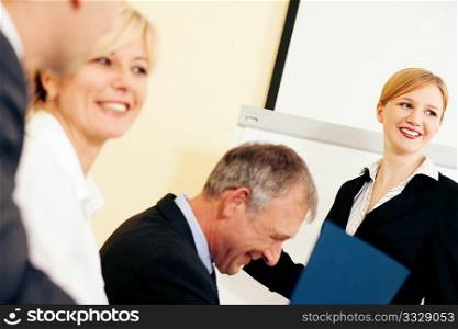 Business team receiving a presentation held by a female co-worker standing in front of a flipchart