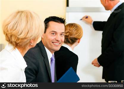 Business team receiving a presentation held by a male co-worker standing in front of a flipchart