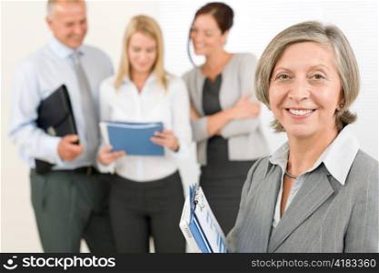 Business team senior businesswoman in front with attractive happy colleagues