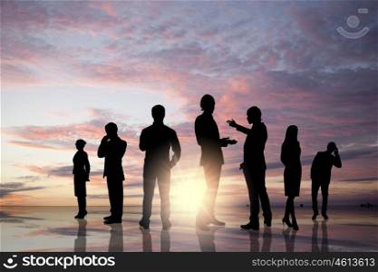 Business team. Silhouettes of business people against sunset landscape