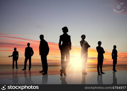 Business team. Silhouettes of business people against sunset landscape