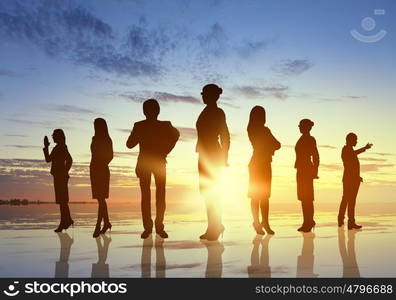 Business team. Silhouettes of business people against sunset landscape