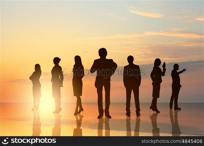 Business team. Silhouettes of business people against sunset landscape