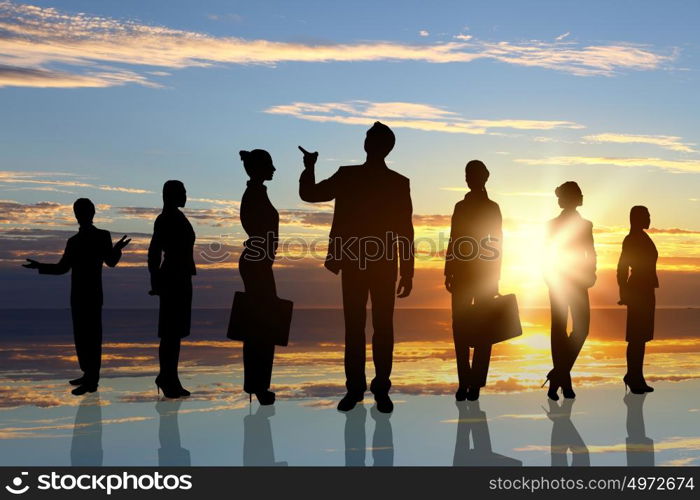 Business team. Silhouettes of business people against sunset landscape