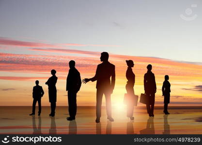 Business team. Silhouettes of business people against sunset landscape