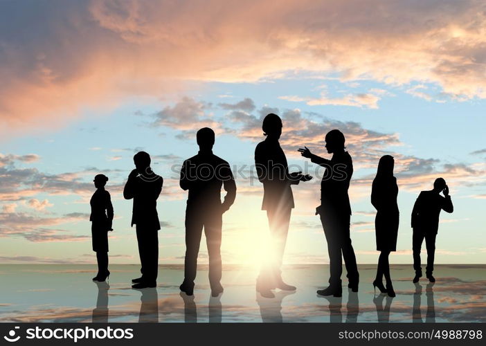 Business team. Silhouettes of business people against sunset landscape