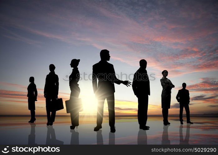 Business team. Silhouettes of business people against sunset landscape